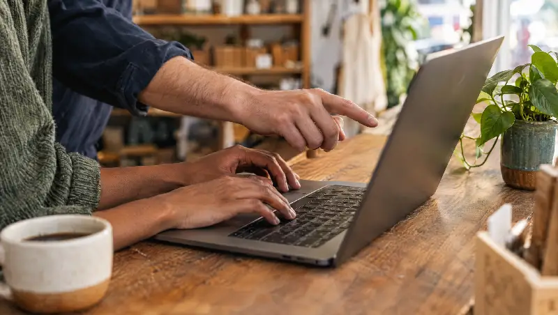 Two people working together at a laptop on a shop counter